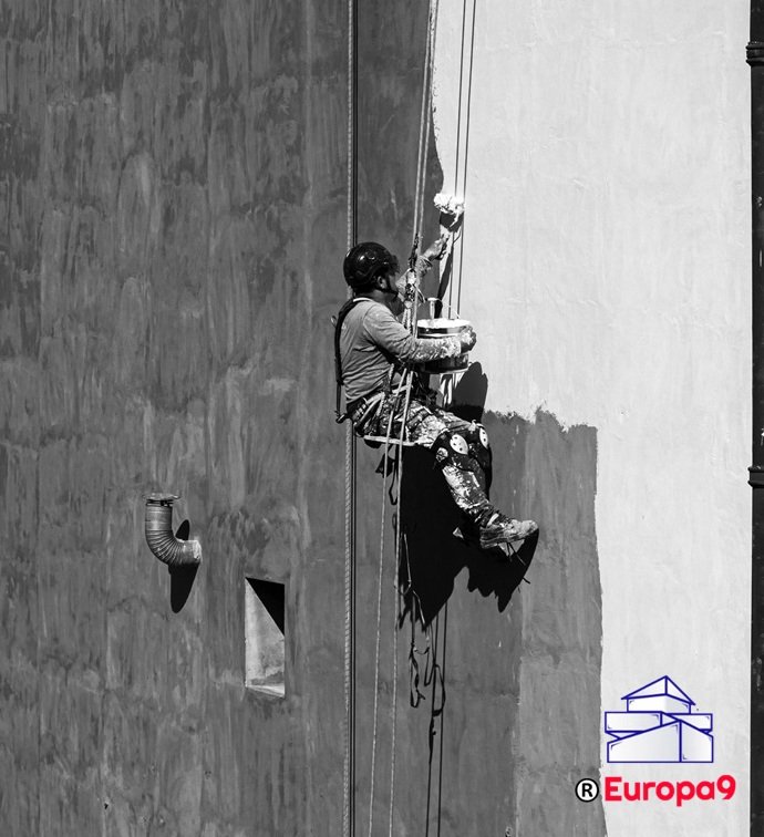 Operario técnico en suspensión realizando el perfilado cromático y protector en un paramento vertical.