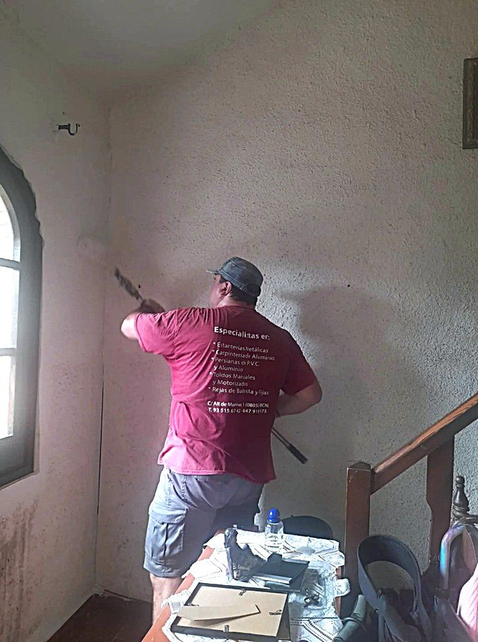 Técnico de la firma Josegra aplicando pintura bactericida con rodillo en una pared texturizada junto a ventana arqueada.
