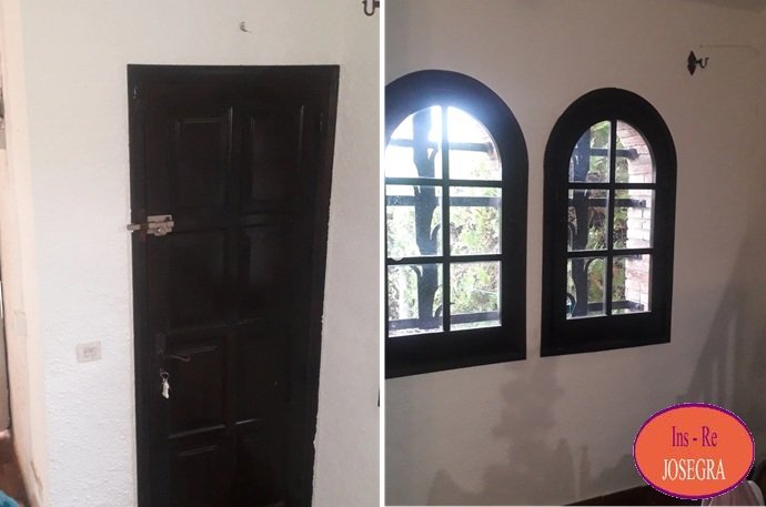 Interior de casa unifamiliar en L'Estartit con muros texturizados, puerta de madera noble y ventanas arqueadas con rejas.